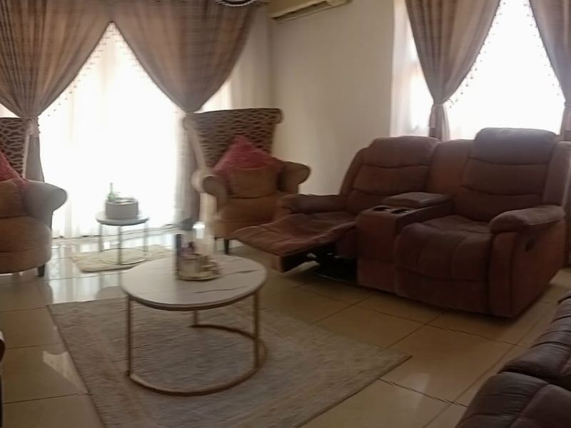 A comfortable living room featuring tiled flooring, a wall-mounted air conditioning unit, and large sliding glass doors that provide natural light.