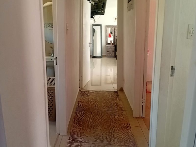 A central hallway with tiled flooring providing access to adjacent rooms, including a bathroom and bedroom.