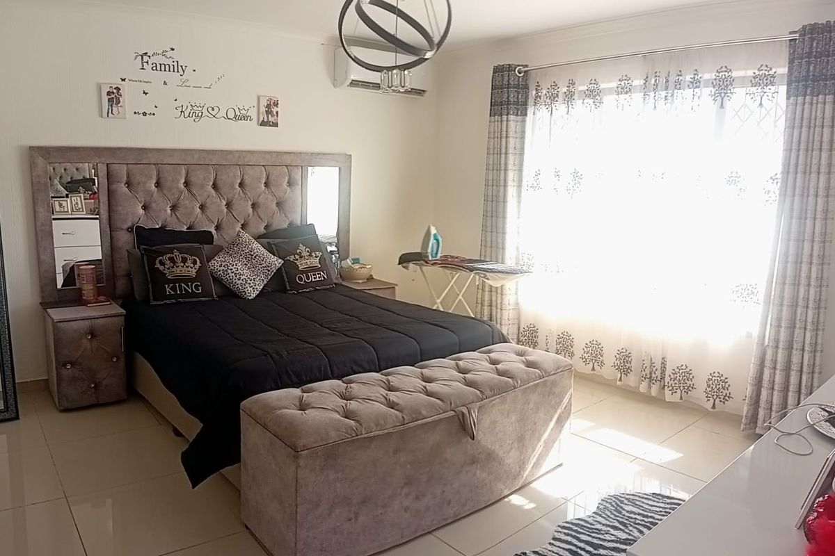 A well-maintained bedroom featuring tiled flooring, an integrated air conditioning unit, and a central ceiling light fixture.
