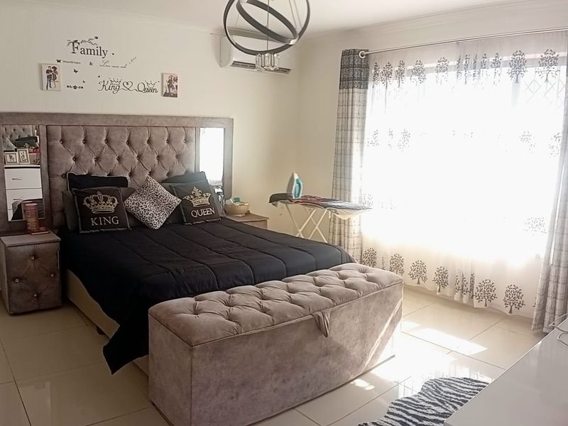 A well-maintained bedroom featuring tiled flooring, an integrated air conditioning unit, and a central ceiling light fixture.