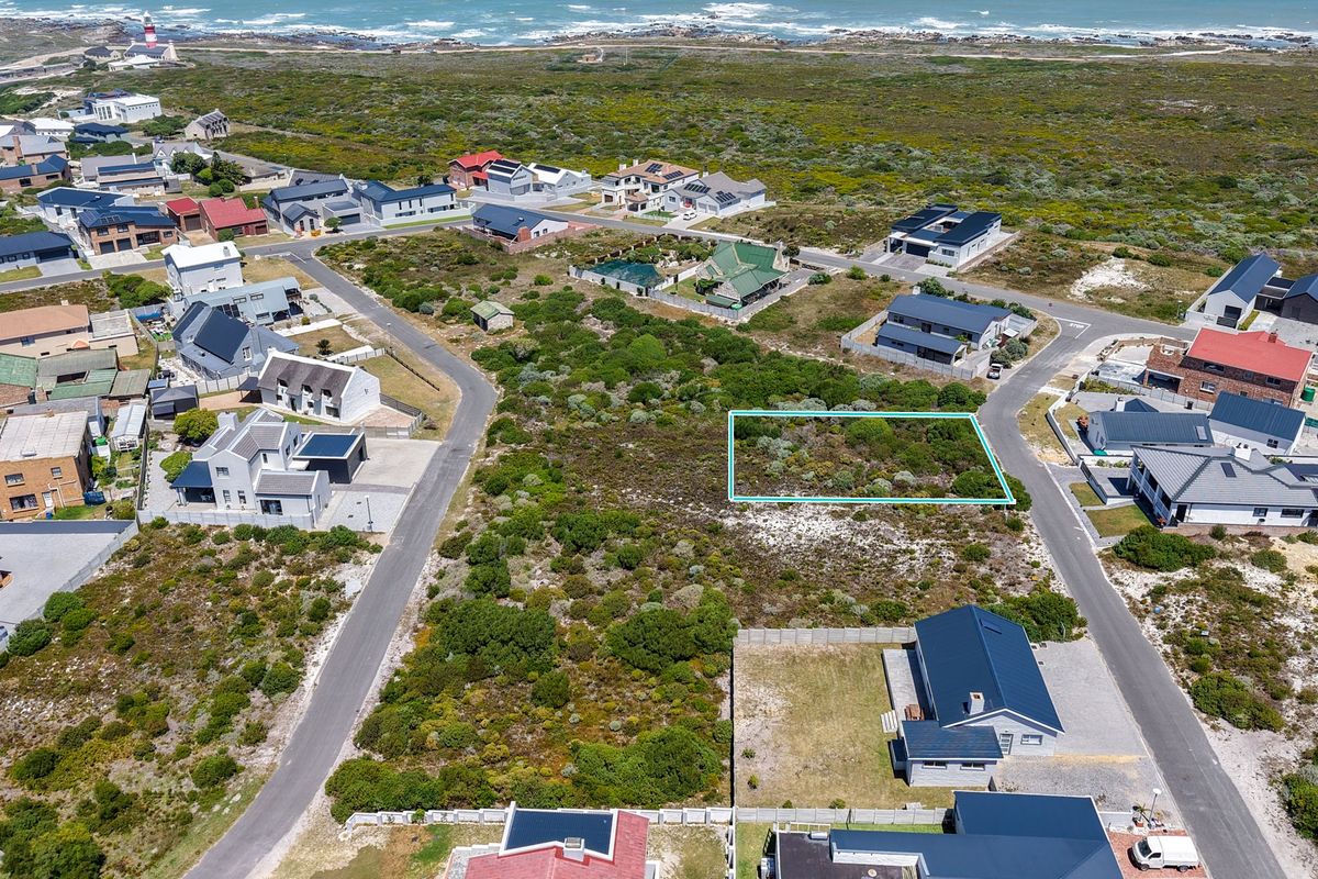 Aerial view of a vacant residential plot situated in a coastal neighborhood, highlighting the surrounding landscape and nearby residential properties.