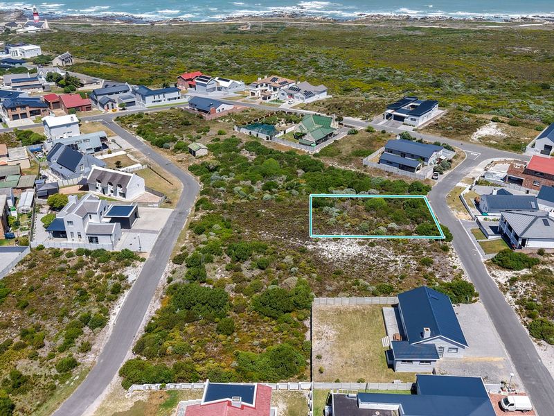 Aerial view of a vacant residential plot situated in a coastal neighborhood, highlighting the surrounding landscape and nearby residential properties.