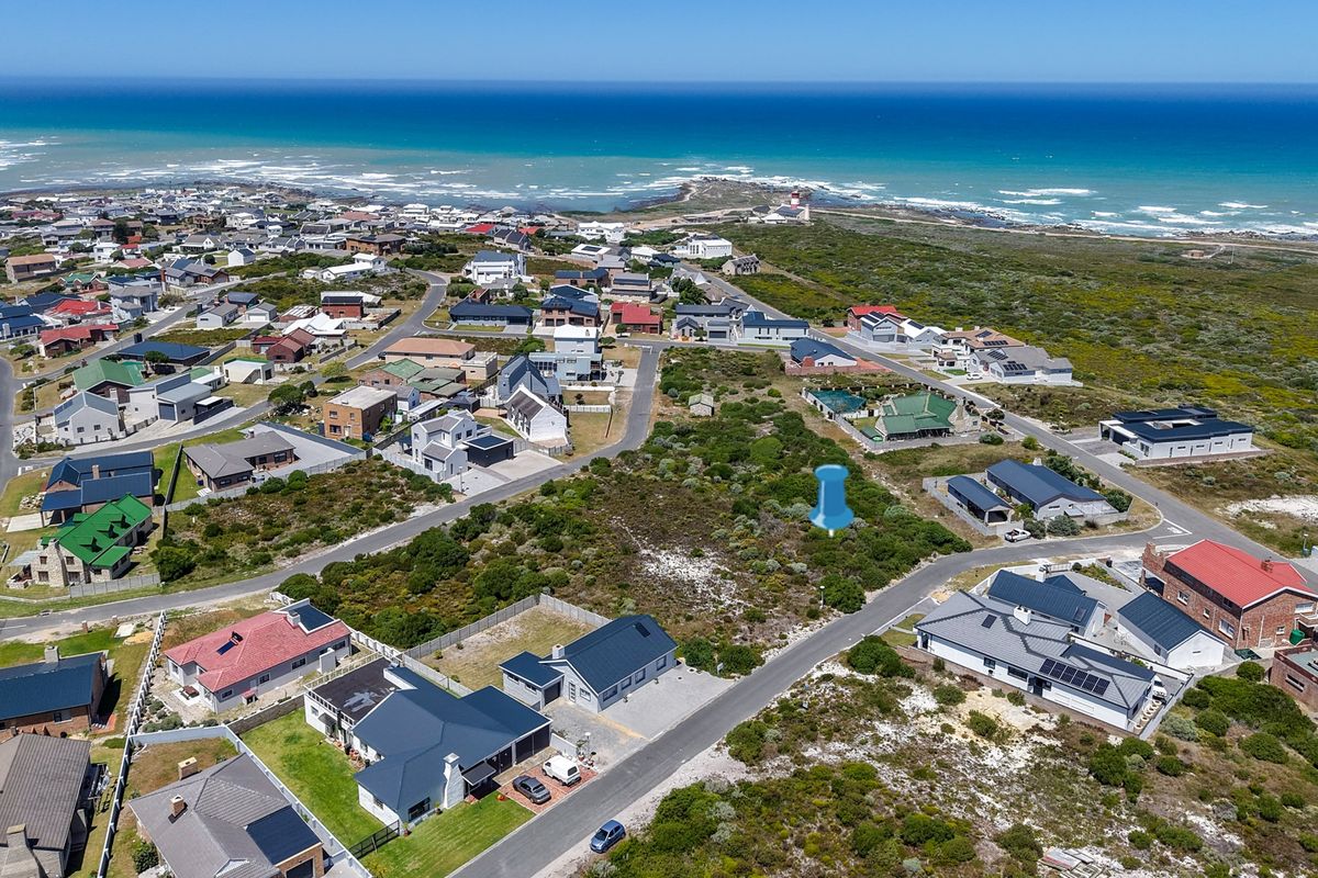 Aerial view of a vacant residential plot situated in a coastal neighborhood, offering proximity to the ocean and established local infrastructure.