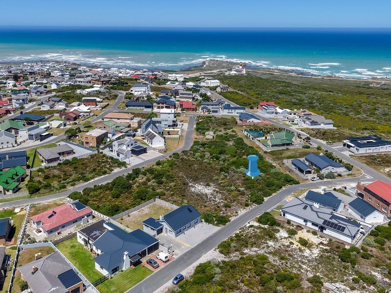Aerial view of a vacant residential plot situated in a coastal neighborhood, offering proximity to the ocean and established local infrastructure.