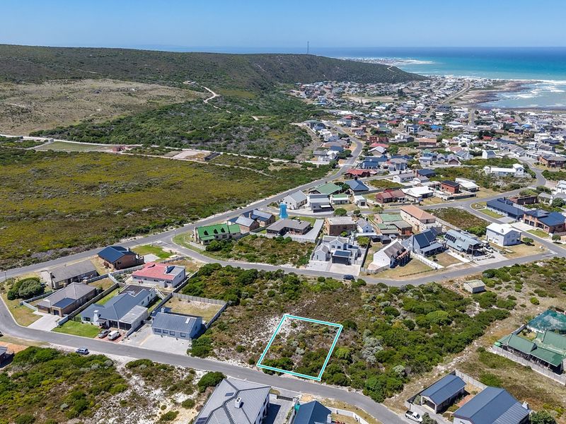 Aerial view of a vacant residential plot situated in a coastal neighborhood, highlighting the surrounding landscape and proximity to the ocean.