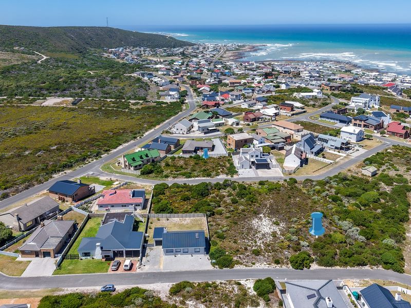 Aerial view of a vacant residential plot situated in a coastal neighborhood, showcasing the surrounding landscape and proximity to the ocean.
