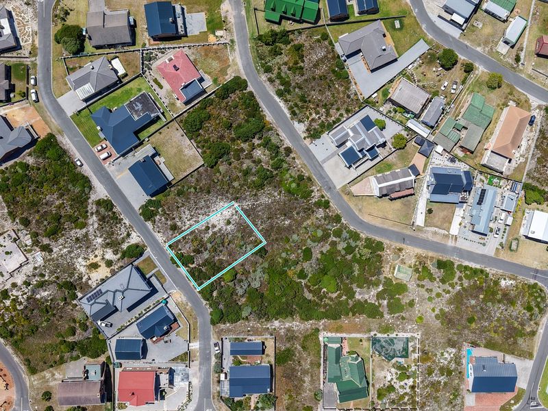 An aerial view of a vacant residential plot situated within an established coastal neighborhood, highlighting the surrounding street layout and existing residential properties.