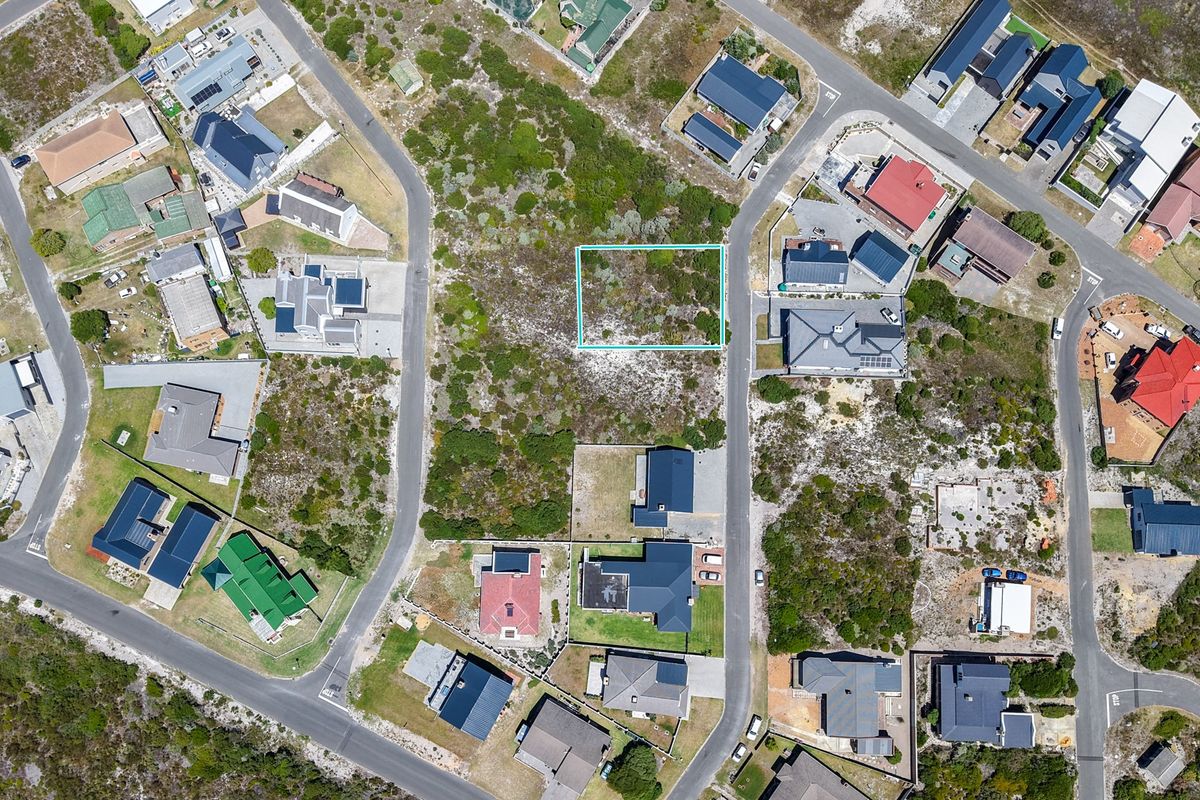 An aerial view of a vacant residential plot situated within an established coastal neighborhood, highlighting the surrounding infrastructure and local landscape.