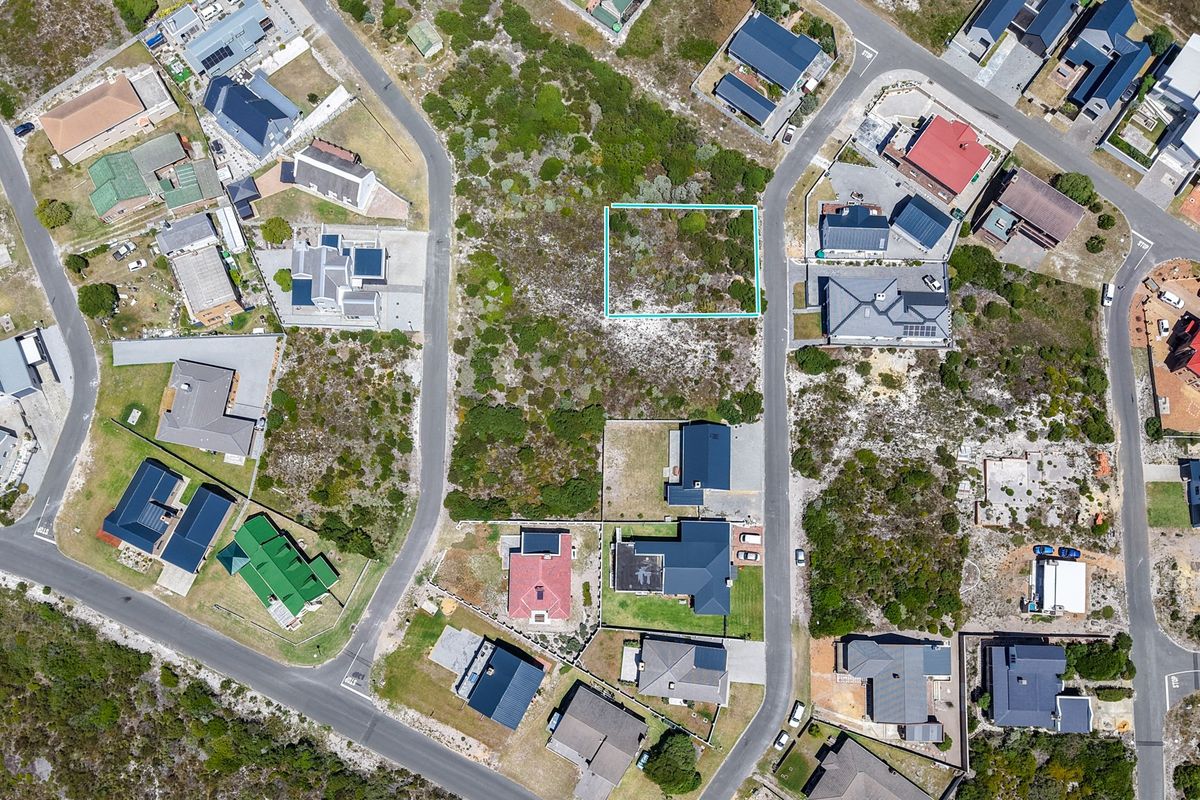 An aerial view of a vacant residential plot situated within a developed coastal neighborhood, highlighting the surrounding infrastructure and natural vegetation.