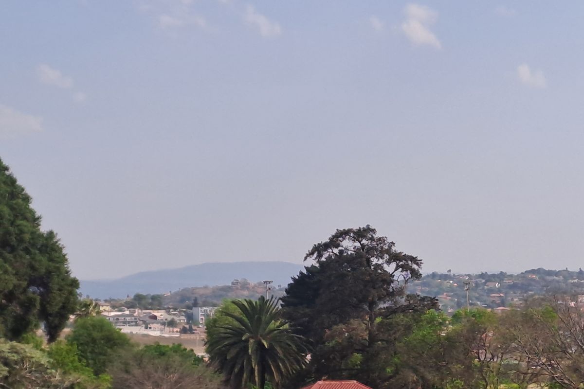 An elevated view overlooking the surrounding neighbourhood, mature trees, and distant hills.