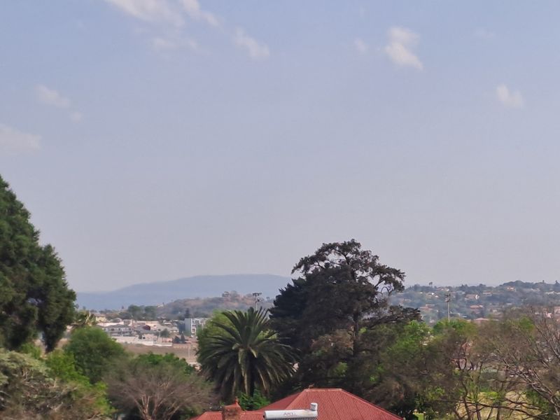 An elevated view overlooking the surrounding neighbourhood, mature trees, and distant hills.