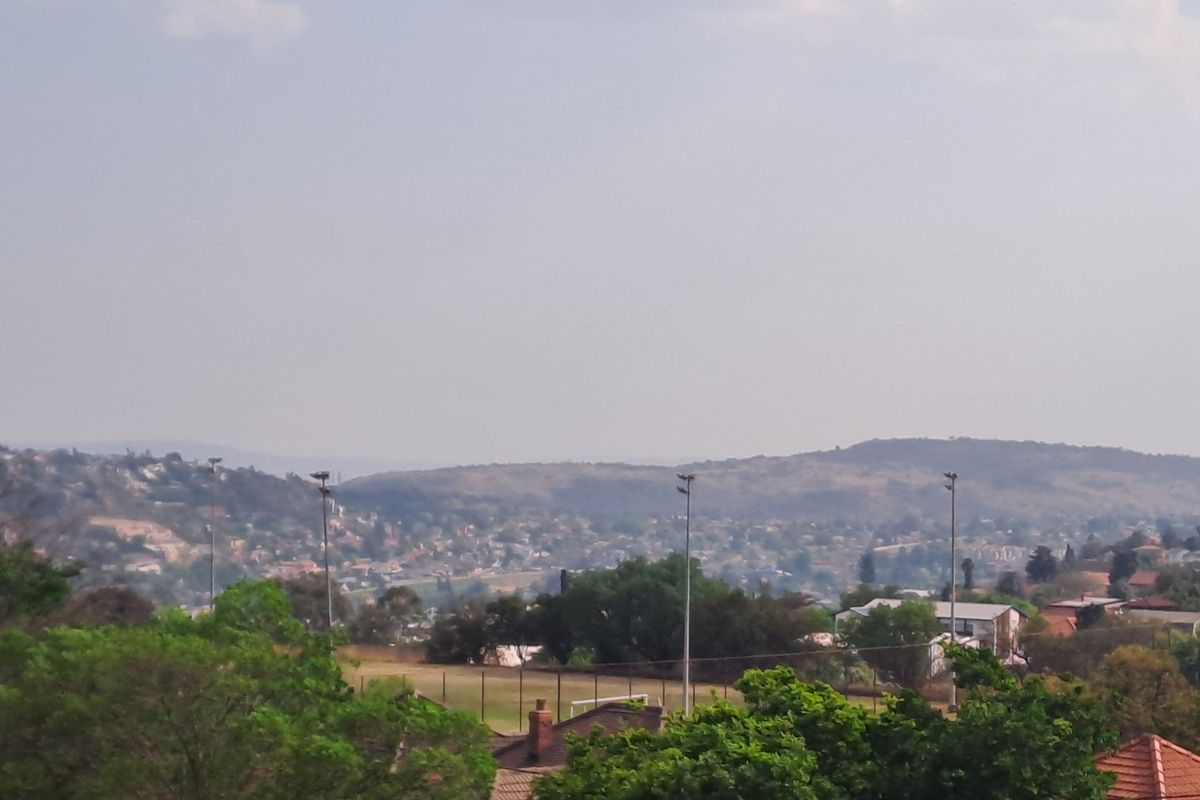 An elevated view overlooking the surrounding neighbourhood, green spaces, and distant hills.
