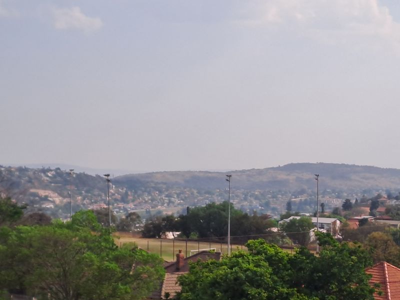 An elevated view overlooking the surrounding neighbourhood, green spaces, and distant hills.