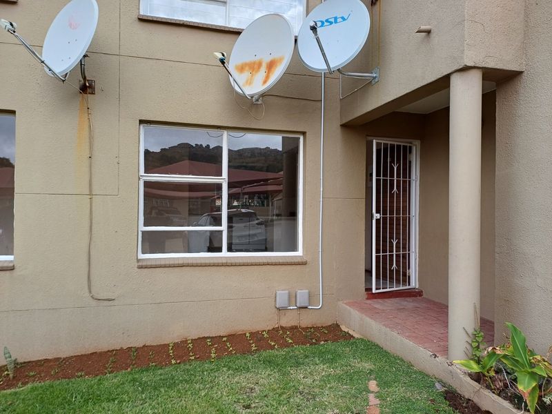Front exterior view of the townhouse featuring a paved entrance, security gate, and multiple satellite dishes mounted on the facade.