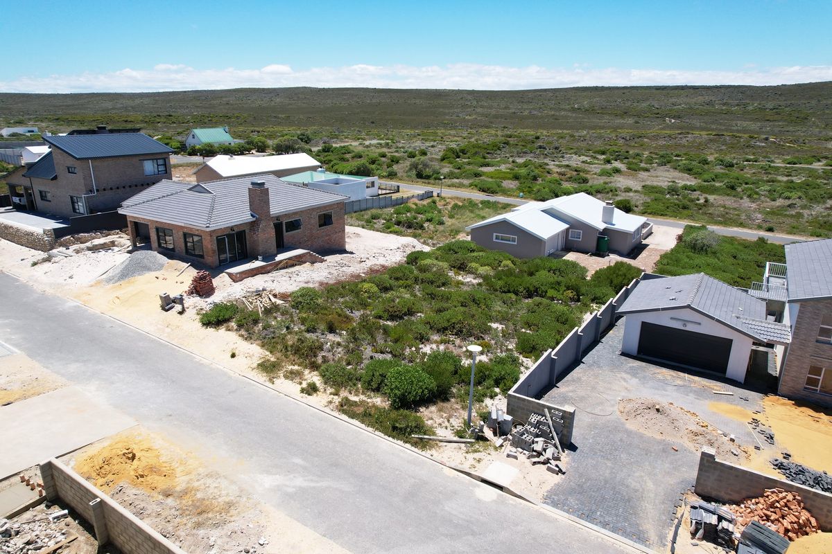 Aerial view of a residential development site showing newly constructed homes, paved driveways, and surrounding natural landscape.