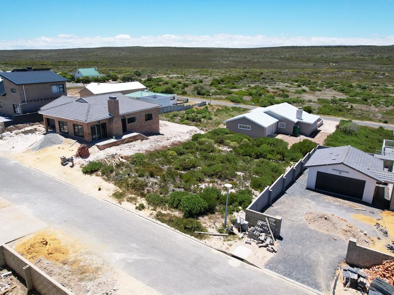 Aerial view of a residential development site showing newly constructed homes, paved driveways, and surrounding natural landscape.