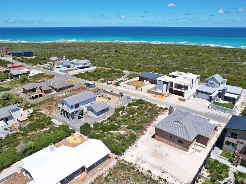 Aerial view of a coastal residential development featuring vacant plots and established homes with direct proximity to the ocean.