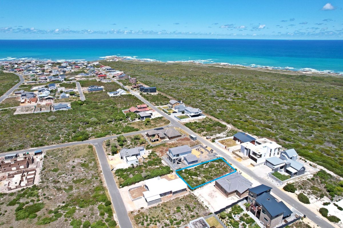 Aerial view of a vacant residential plot situated in a coastal neighborhood, offering proximity to the ocean and established surrounding infrastructure.