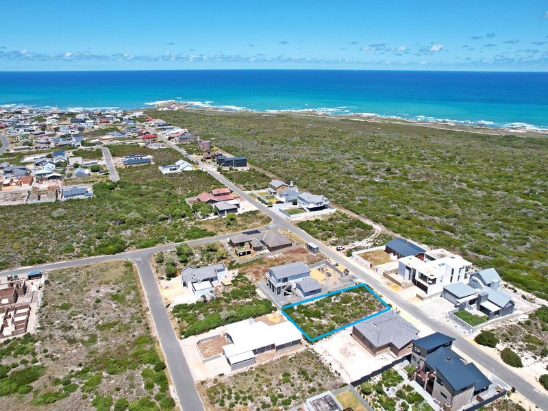 Aerial view of a vacant residential plot situated in a coastal neighborhood, offering proximity to the ocean and established surrounding infrastructure.