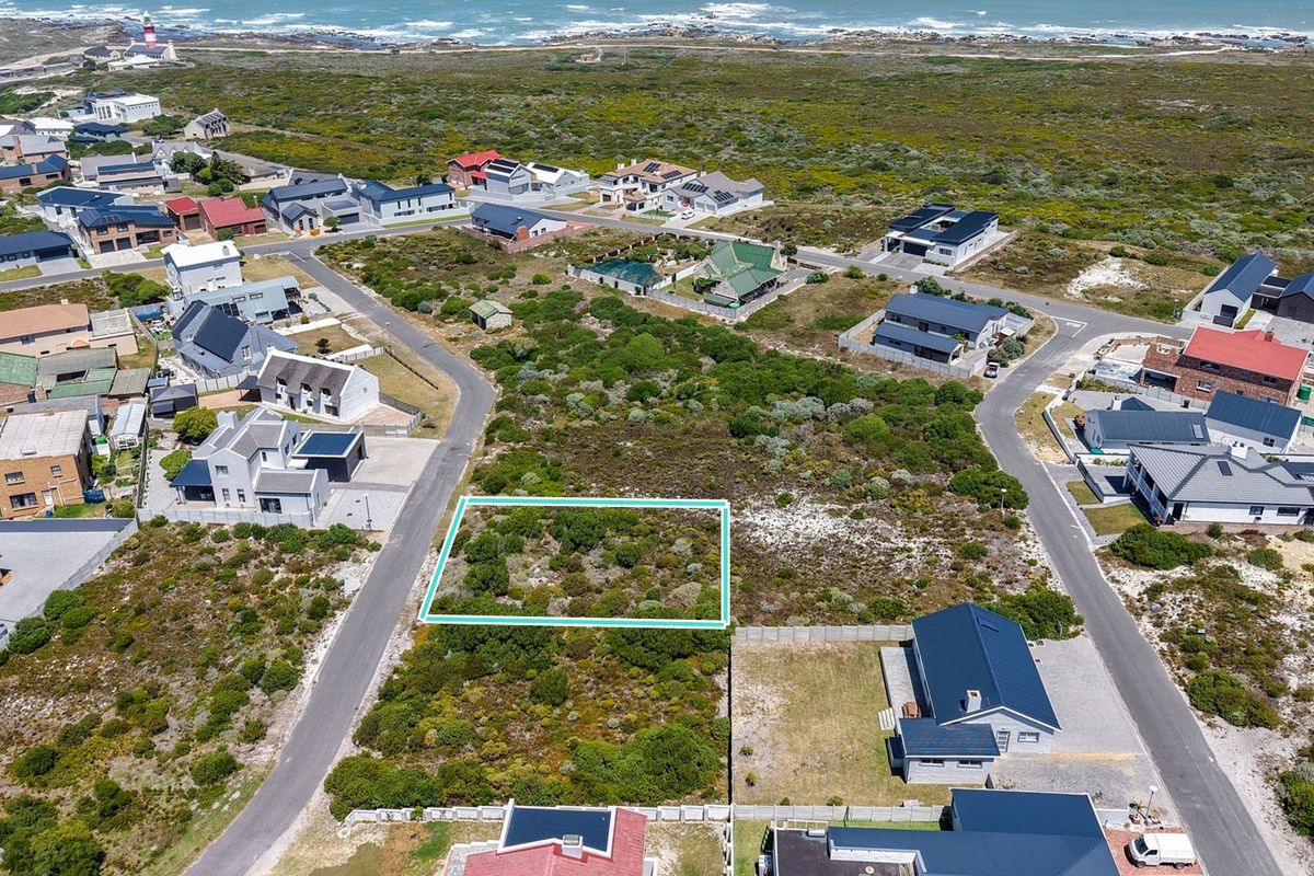 An aerial view of a vacant residential plot situated in a coastal neighborhood, highlighting the surrounding landscape and proximity to the ocean.
