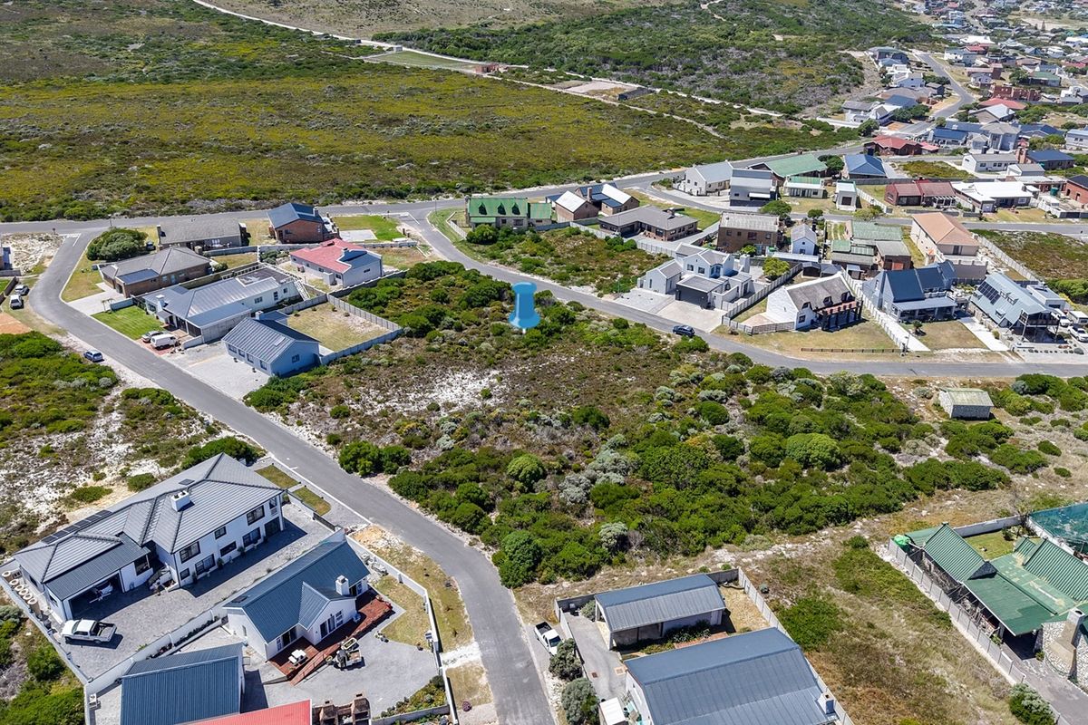 Aerial view of a vacant residential plot situated in a developed coastal neighborhood with established road access and surrounding residential properties.