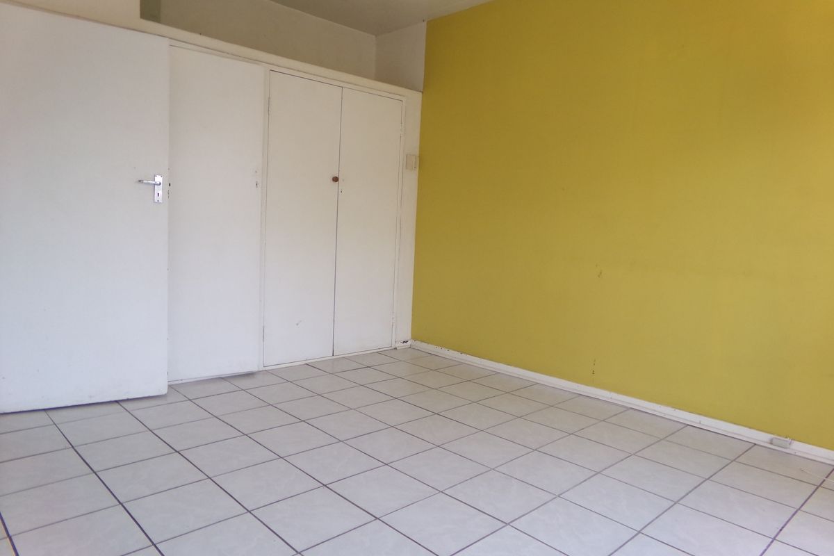 An empty bedroom featuring tiled flooring and built-in cupboards, ready for a fresh coat of paint and new interior design.