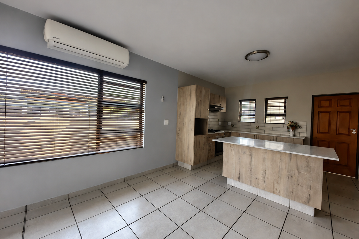 Modern kitchen featuring light wood-look cabinetry, stone countertops, a central island, tiled flooring, and an integrated air conditioning unit.