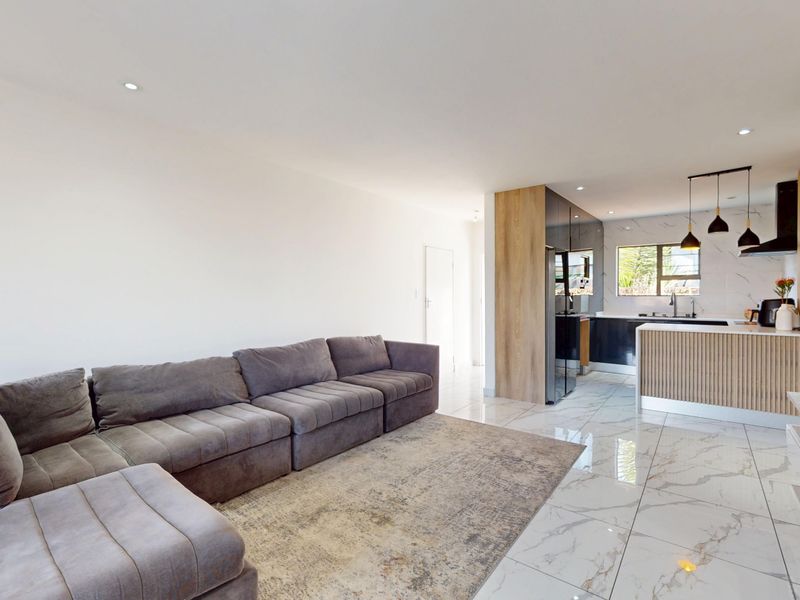 Modern open-plan living and kitchen area featuring marble-look floor tiles, contemporary cabinetry, and a stylish kitchen island with integrated lighting.