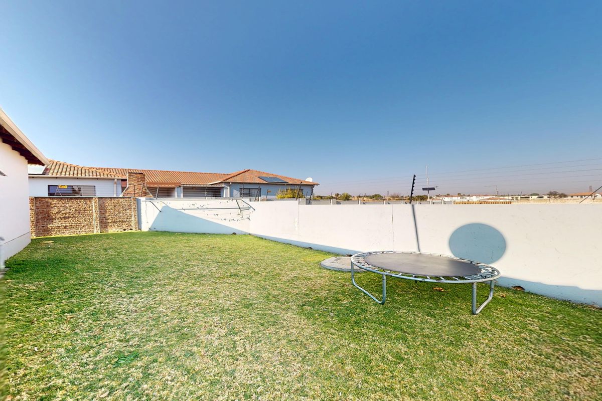 A private rear garden area featuring a lawn, perimeter boundary walls, and installed electric fencing for added security.