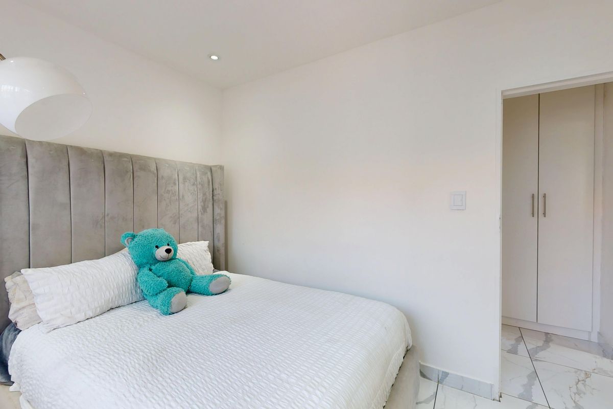 A bright bedroom featuring modern tiled flooring, recessed ceiling lighting, and built-in cupboards for storage.