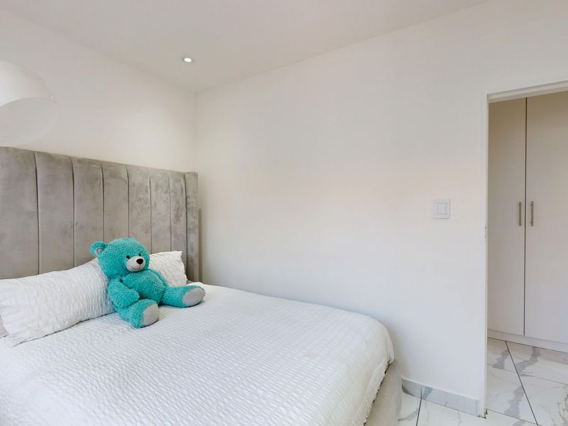 A bright bedroom featuring modern tiled flooring, recessed ceiling lighting, and built-in cupboards for storage.
