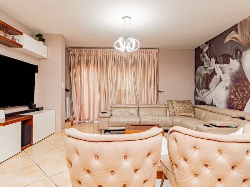 A well-maintained living room featuring tiled flooring, modern lighting, and built-in shelving, with direct access to an outdoor area through sliding glass doors.