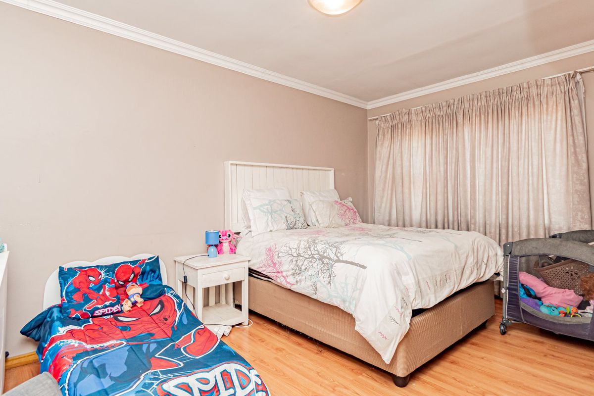 A bedroom featuring laminate flooring and crown molding, providing a functional space with neutral wall tones and window treatments.