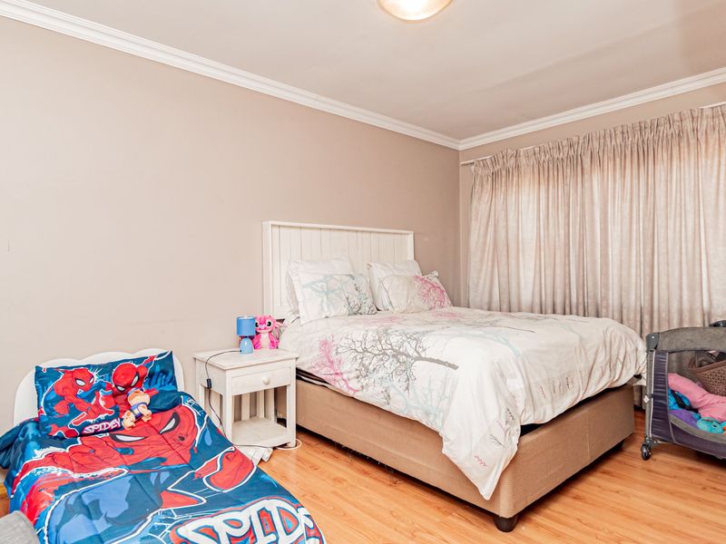 A bedroom featuring laminate flooring and crown molding, providing a functional space with neutral wall tones and window treatments.