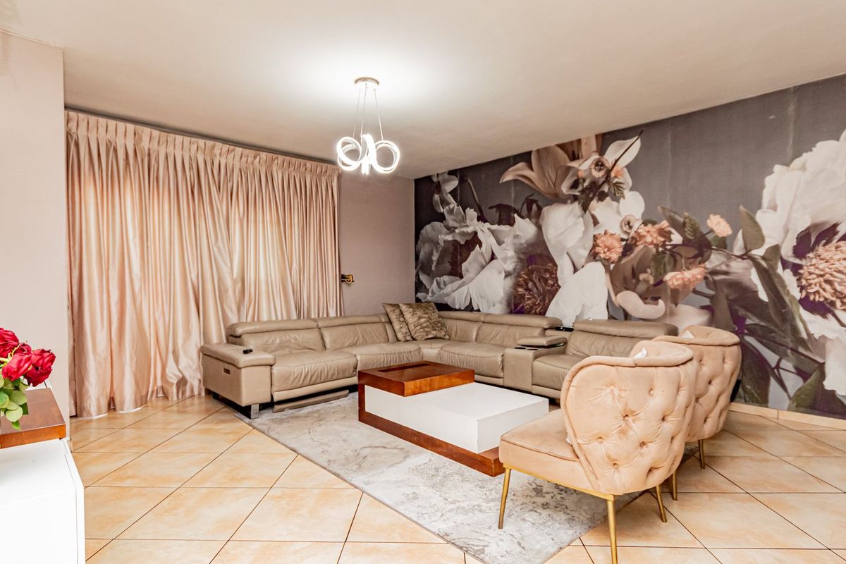 A well-maintained living room featuring large format floor tiles, a modern pendant light fixture, and a decorative feature wall.