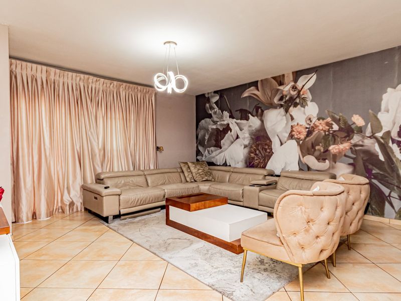 A well-maintained living room featuring large format floor tiles, a modern pendant light fixture, and a decorative feature wall.