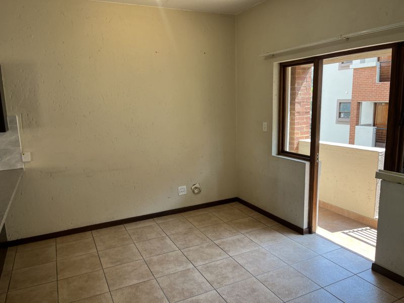 An empty living area featuring tiled flooring and a sliding glass door providing access to an outdoor balcony.