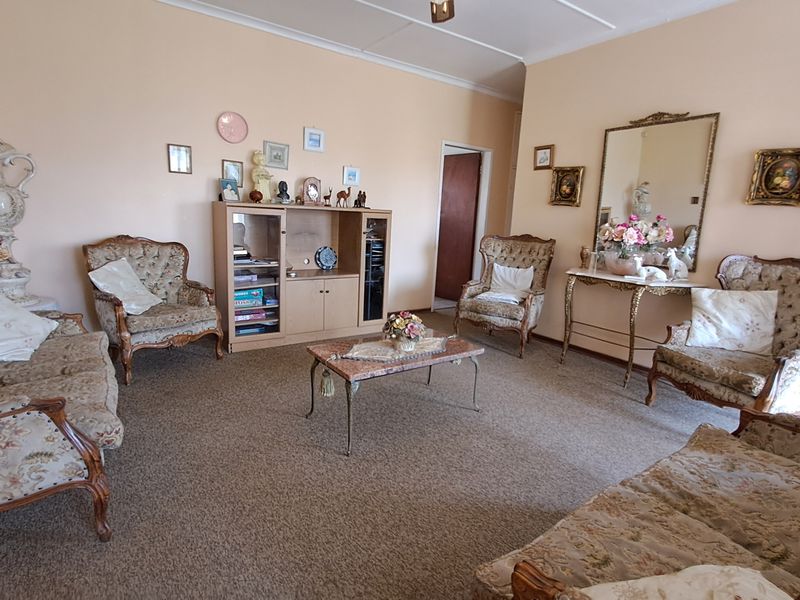 A spacious living room featuring carpeted flooring and coved ceilings, offering a traditional layout ready for modern updates.