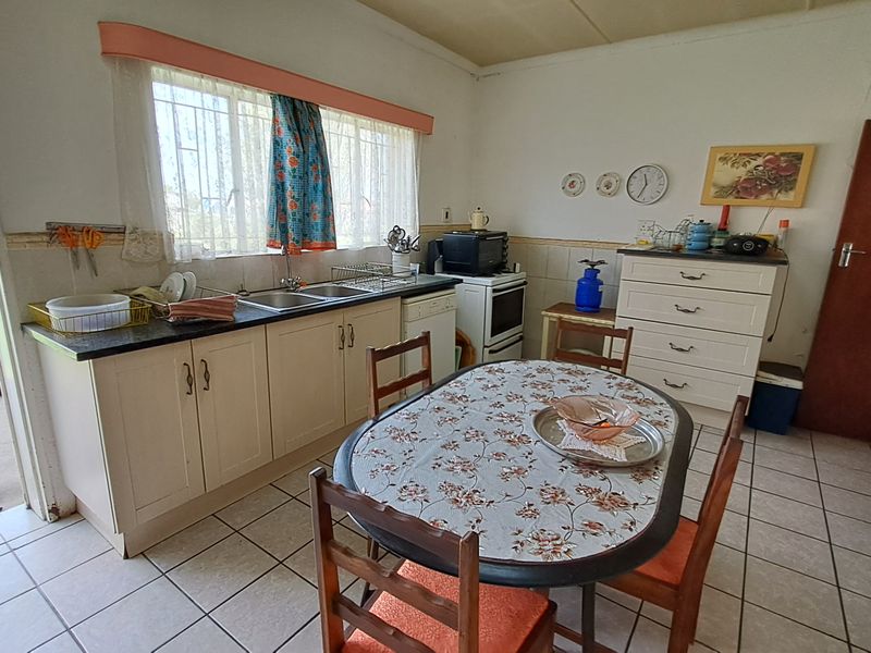 A functional kitchen featuring tiled flooring, built-in cabinetry, a double basin sink, and a freestanding stove with direct access to the garden.