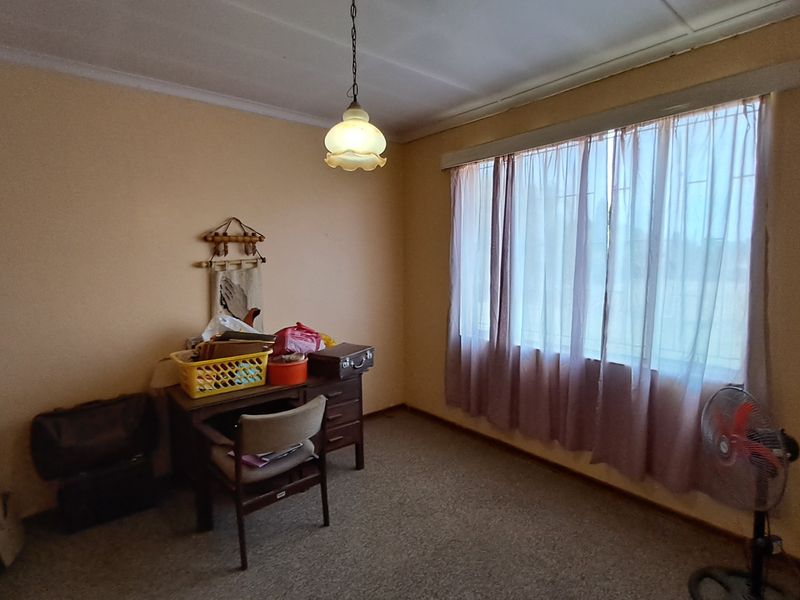 A bedroom featuring built-in cupboards, carpeted flooring, and a pendant light fixture, offering a functional space with potential for modernization.
