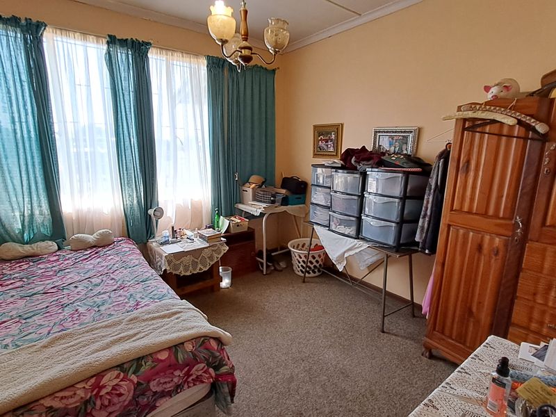 A bedroom featuring carpeted flooring and large windows with curtain rails, offering a functional space ready for cosmetic updates.
