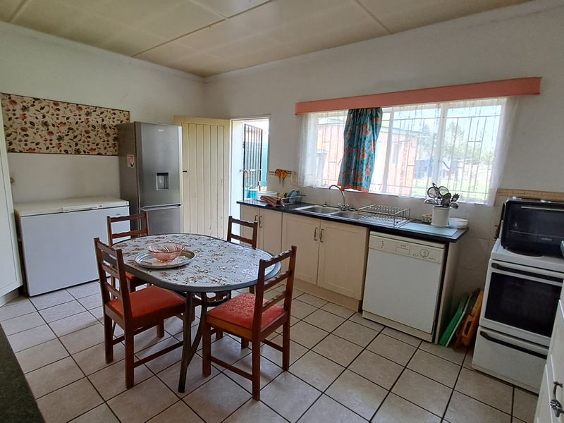 A functional kitchen featuring tiled flooring, built-in cabinetry, a double basin sink, and a freestanding stove with an extractor fan.