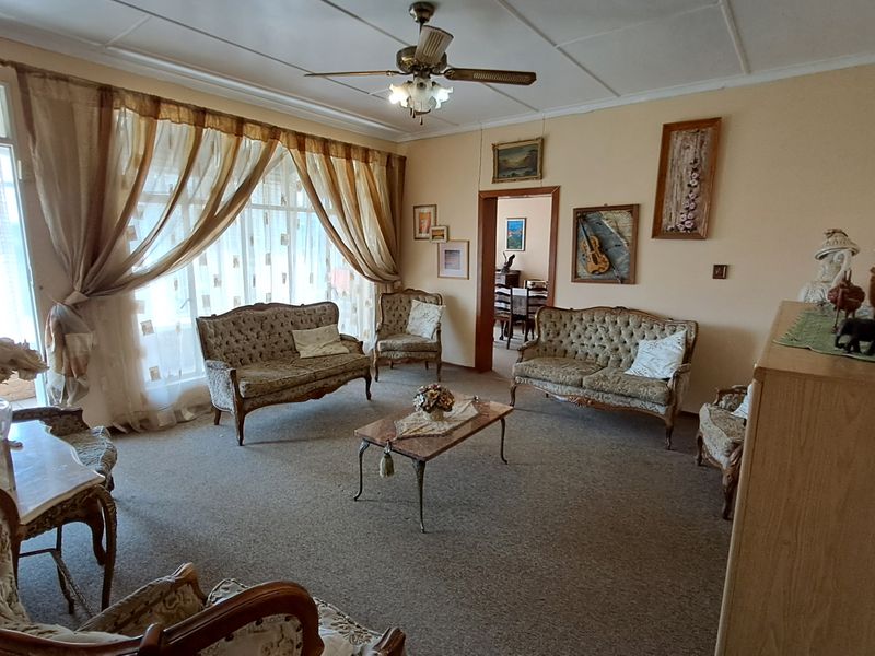 A spacious living room featuring carpet flooring, a ceiling fan, and large sliding glass doors providing natural light.