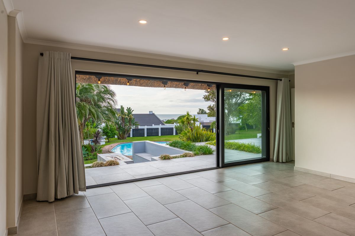 Spacious living area featuring large sliding glass doors that open onto a patio with pool views, finished with neutral floor tiles and recessed lighting.