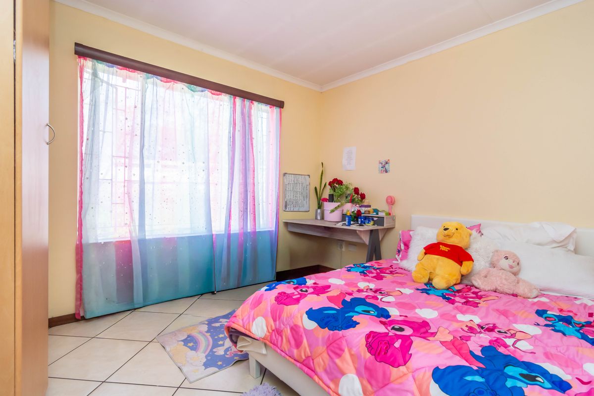 A bedroom featuring tiled flooring, a built-in wardrobe, and a window fitted with security bars, providing a functional space.