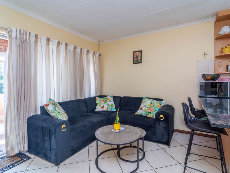 Open-plan living area featuring tiled flooring, a built-in shelving unit, and a granite breakfast bar, with direct access to an outdoor patio.