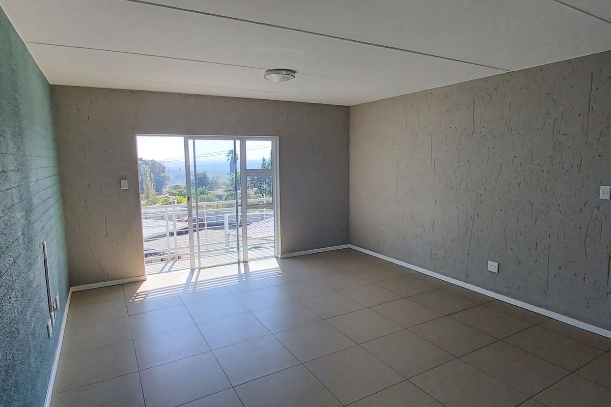 An empty living room featuring tiled flooring, a textured feature wall, and a sliding glass door providing access to an outdoor area.