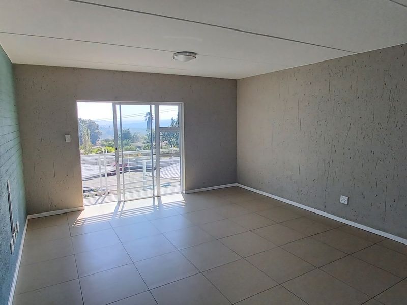 An empty living room featuring tiled flooring, a textured feature wall, and a sliding glass door providing access to an outdoor area.