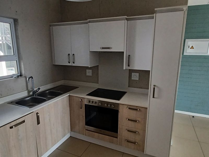 Modern kitchen featuring built-in cabinetry, laminate countertops, stainless steel sink, and integrated electric oven and hob.