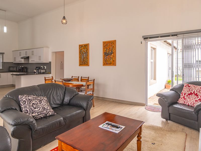 Open-plan living and dining area featuring laminate flooring, a functional kitchen with built-in cabinetry, and direct access to an outdoor patio through sliding doors.
